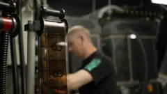 A strip of IMAX 70mm film in the foreground with countdown numbers. A man works behind it.