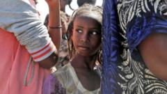An Ethiopian girl stands in line to receive food, at a transit camp, which houses refugees fleeing the fighting in the Tigray region, on the border in Sudan