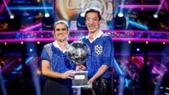 Karen Carney and Carlos Gu with their trophy after winning the 2025 series of Strictly Come Dancing.