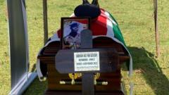 Coffin on Ole Kiyaipi with the Kenyan flag draped over it and a photo of him