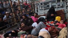 Wounded Palestinians in a lorry with a cage as people look at the from outside