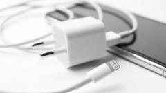 Кабель для зарядки iPhone и адаптер питания USB лежат поверх iPhone