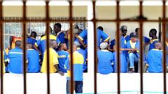 Prisoners are seen at the Makala prison in Kinshasa on December 18, 2012 from behind the bars of the windows of a court room.