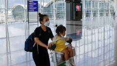 香港国际机场客运大楼内一位女士用手推车推着一位小女孩前行（1/8/2022）