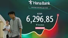 A man and a woman walk past an electronic screen showing 31 July's Kospi trading figures