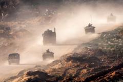 Israeli army humvees and vehicles move along a dirt road in the Gaza Strip near a position along the border with southern Israel on 4 January 2024
