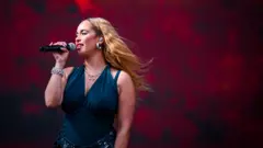 Jorja Smith on stage with a microphone in a blue outfit