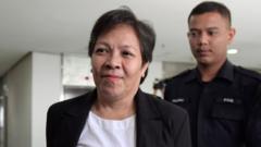 Maria Elvira Pinto Exposto (L), 54, is escorted upon her arrival at the Shah Alam High Court ahead of the verdict in her drugs conviction in Shah Alam, outside Kuala Lumpur, on December 27,