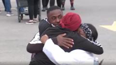 Dos estudiantes abrazan a un adulto después de evacuar la escuela.