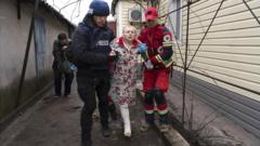 Евгений Малолетка помогает парамедику транспортировать женщину, пострадавшую во время обстрела в Мариуполе