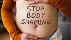 A woman with Stop Body Shaming written on her belly