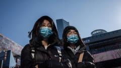 People wear protective masks as they walk outside a shopping mall in Beijing on January 23