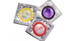 Three coloured condoms in foil and plastic wrappers
