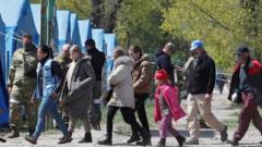 Civilians who left the area near Azovstal steel plant in Mariupol walk accompanied by UN staff