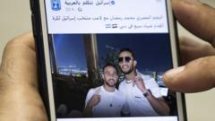 A man holds a mobile phone showing a Facebook post by the Israeli government featuring a photo of Egyptian singer Mohamed Ramadan and Israeli footballer Diaa Saba