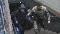 An Ukranian soldier helps a woman as displaced Ukrainians take a train from the Lviv train station in western Ukraine,