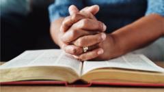 Mulher com as mãos em oração sobre uma Bíblia aberta