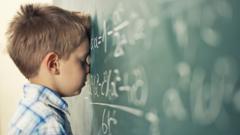 Young boy leans against chalkboard