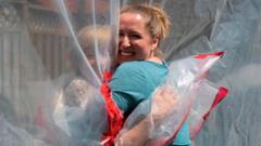 Two women hug through a clear plastic sheet