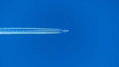 Avião voando e fazendo rastro de fumaça branca no céu