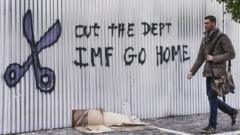 Homem passa em frente a grafite com palavras de ordem contra o FMI em fevereiro de 2015 em Atenas, na Grécia