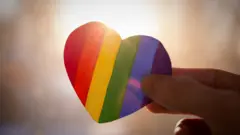 Getty Images Rainbow coloured paper heart held in hand