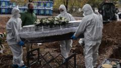 Gravediggers wearing personal protective equipment (PPE) carries a coffin during a funeral for a Covid-19 coronavirus victim at a cemetery in Thessaloniki on December 5, 2020. - More than 2,800 people have died of the virus, including 98 on December 4, and over 600 people are in intensive care.