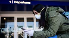 A passenger wearing a protective face mask looks her phone in Linate Airport in Milan