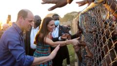 O duque e a duquesa de Cambridge cumprimentam crianças jamaicanas por uma cerca de arame