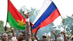 Сторонники нового лидера хунты Буркина-Фасо Ибрагима Траоре держат национальные флаги Буркина-Фасо и России во время демонстрации возле штаб-квартиры национального радио и телевидения в Уагадугу, 6 октября 2022 г.
