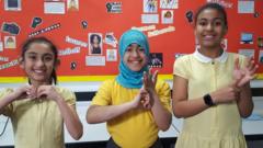 Children spell out the letters BSL in sign language.