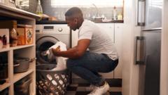 Homem botando roupa na máquina de lavar