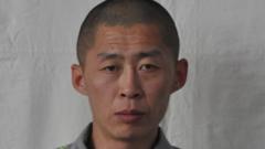 North Korean prisoner Zhu Xianjian stands against grey backdrop