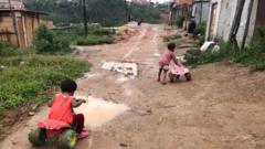 Crianças andando com motos de brinquedo em rua de lama na ocupação Terra de Deus