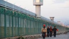 Workers walk by the perimeter fence of what is officially known as a vocational skills education centre in Dabancheng in Xinjiang Uighur Autonomous Region, China September 4, 2018.