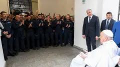 Papa Francisco em uma cadeira de rodas enquanto o pessoal da prisão o aplaude.