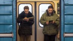 Moscow commuters reading handheld devices on a metro train