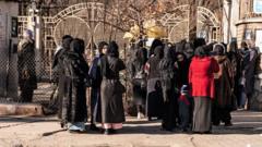 Afghan female university students stop by Taliban security personnel stand next to a university in Kabul on December 21, 2022.