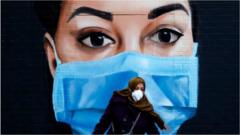 Женщина в маске на фоне настенного портрета