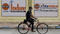 Hombre en bicicleta pasa por una gasolinera en Calcuta mientras suben los precios del petróleo