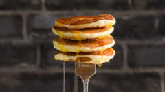 Stack of pancakes with syrup held up on a fork