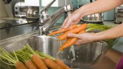 Mulher lavando cenoura na pia da cozinha