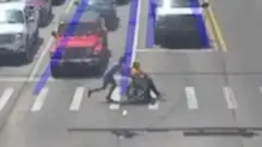 Man dressed as Spider-Man pushes wheelchair user across a crossing