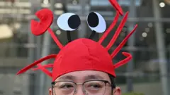 A man wears a lobster hat that represent the OpenClaw logo, an open-source AI assistant at the Baidu headquarter in Beijing on March 11, 2026