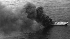 Imagem aérea e em preto e branco de navio queimando no meio do mar