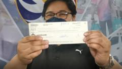 A lottery winner poses with a cheque.