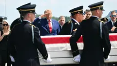 President Trump salutes the coffin of a fallen service member.