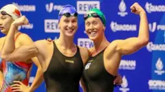 Nel family Olivia and Georgia Nel in black swimming costumes after a race, with their arms held aloft.