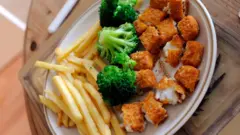 A plate of chips, chopped up fish fingers and broccoli. 