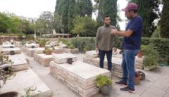 مراسل بي بي سي في القدس مهند توتنجي وهو يجري حوار مع يوني حول حصوله على بطاقة هوية الجندي المدفون في هذه المقبرة